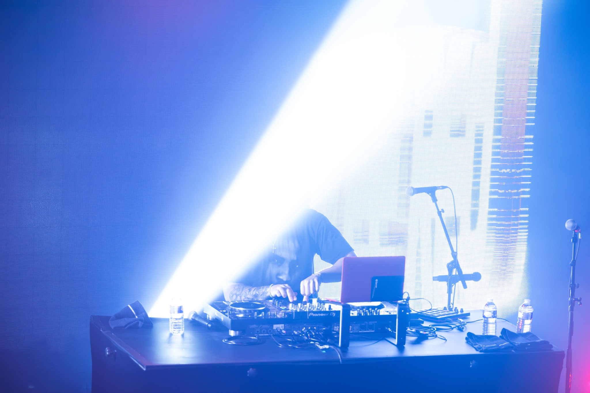 DJ derrière ses platines sous un faisceau bleu