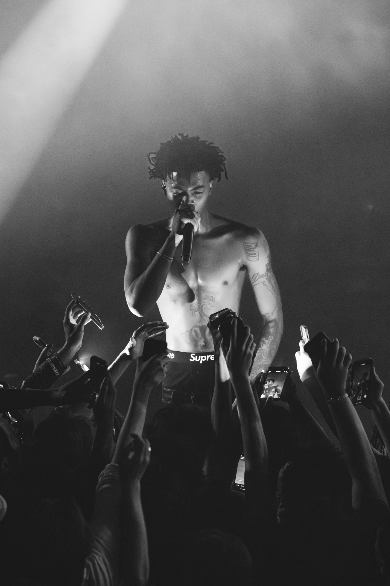 Portrait d’un chanteur entouré de téléphones en noir et blanc