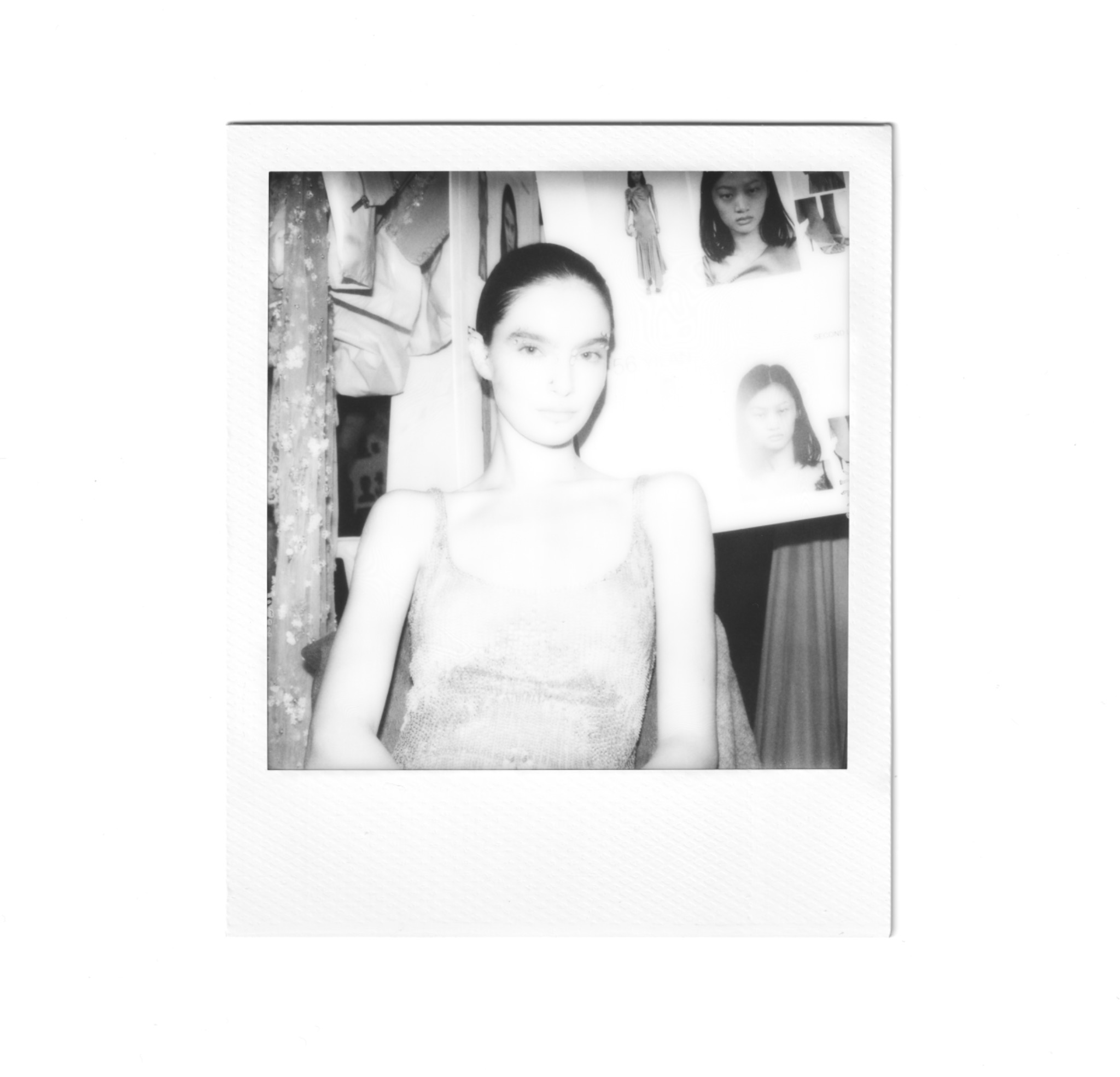 Portrait backstage au Polaroid devant un portant de vêtements