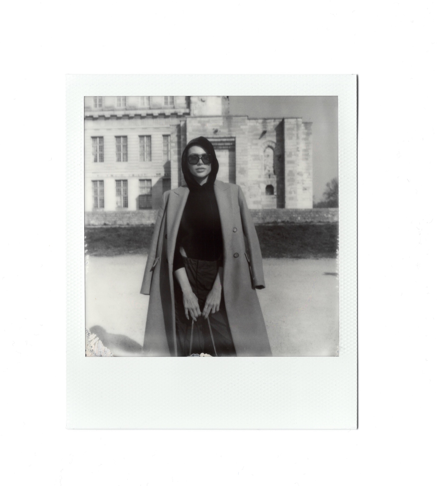 Portrait en manteau et lunettes au Polaroid